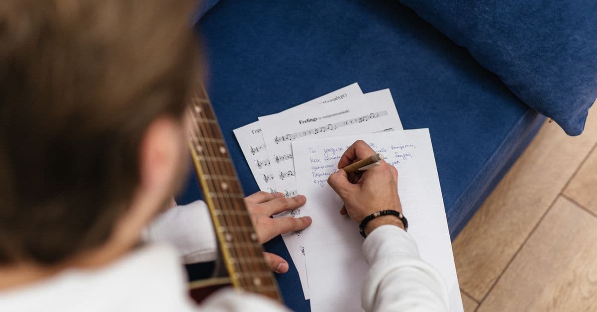 Violão e caderno de letras de música — Músicas curtas: o repertório certo pra aulas de 25 minutos