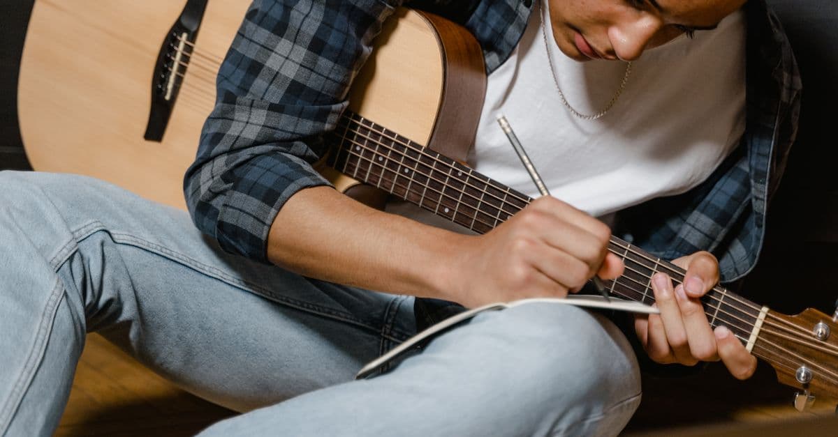 Violão e caderno de letras de música — Músicas ideais pra fixar o Present Simple com rotina e hábitos