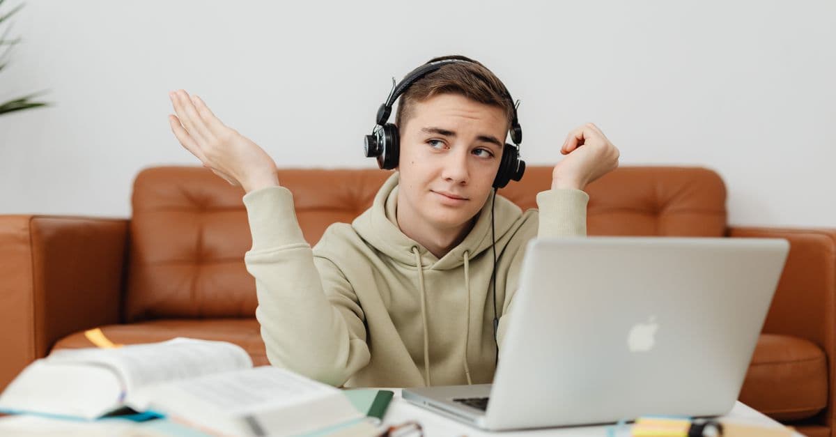 Aluno estudando inglês com fones e notebook — 5 músicas para praticar presente simples com alunos A1