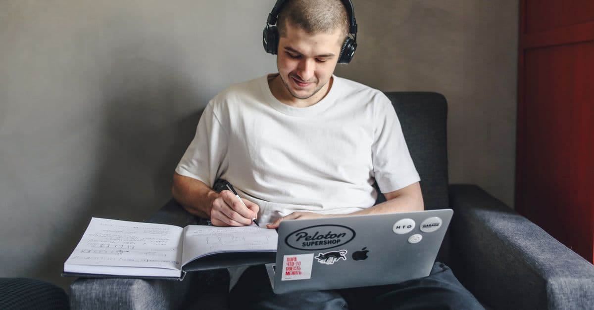 Aluno estudando inglês com fones e notebook — Quanto tempo da aula dedicar à música sem perder outros conteúdos
